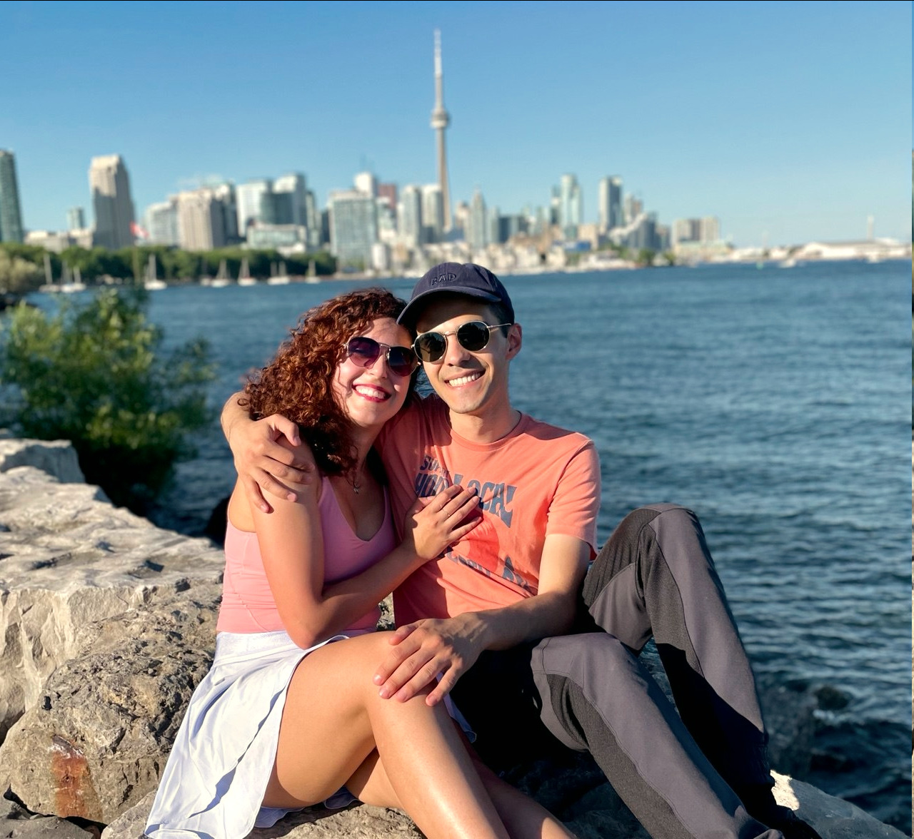 Shirin and Pasha sitting together on rocks with the Toronto skyline behind them